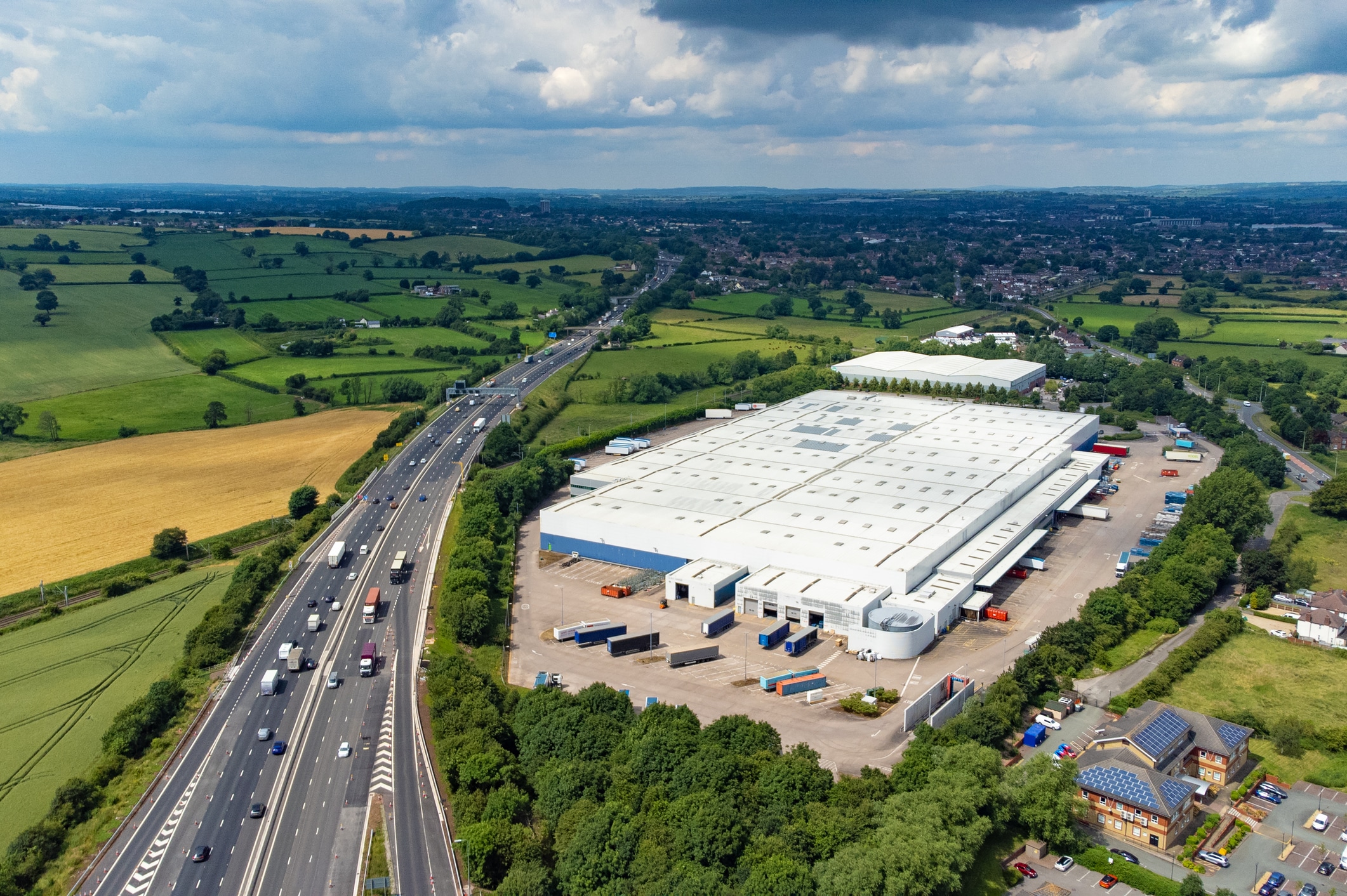 Wide angle aerial view of a large warehouse distribution centre next to the M6 motorway in the West Midlands, England, UK.